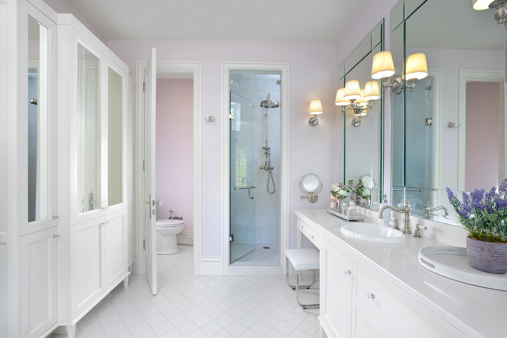 トロントにある広いトラディショナルスタイルのおしゃれなマスターバスルーム (白いキャビネット、ピンクの壁、オーバーカウンターシンク、白い床、シェーカースタイル扉のキャビネット、置き型浴槽、一体型トイレ	、珪岩の洗面台、アルコーブ型シャワー、開き戸のシャワー、トイレ室) の写真