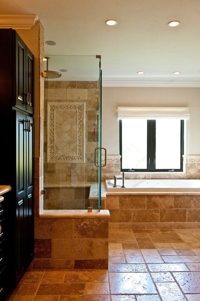 Design ideas for a large mediterranean ensuite bathroom in Miami with raised-panel cabinets, dark wood cabinets, a built-in bath, a built-in shower, a one-piece toilet, beige tiles, brown tiles, stone tiles, beige walls, travertine flooring, brown floors and a hinged door.