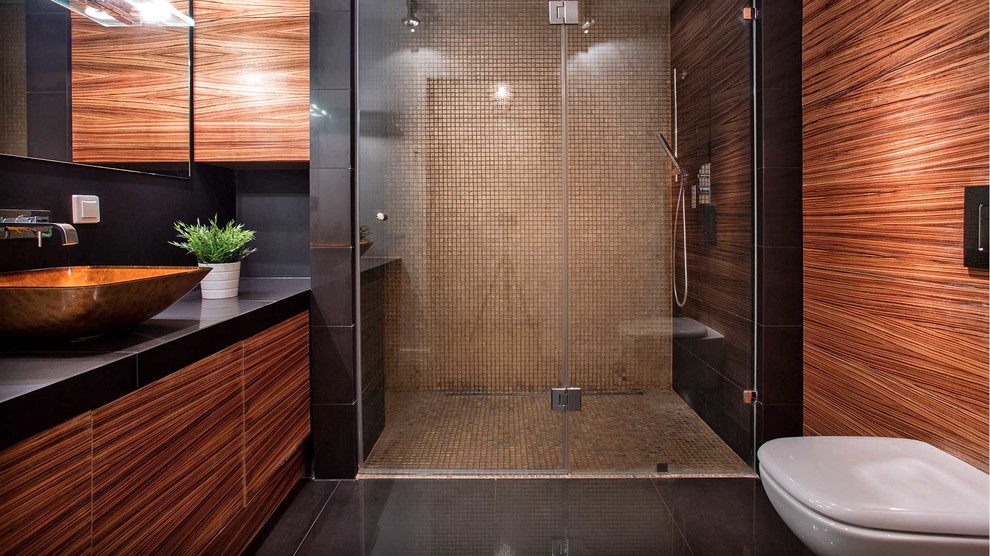 Inredning av ett modernt mellanstort svart svart badrum med dusch, med släta luckor, bruna skåp, en dusch i en alkov, brun kakel, mosaik, ett fristående handfat, bänkskiva i akrylsten, svart golv och dusch med gångjärnsdörr
