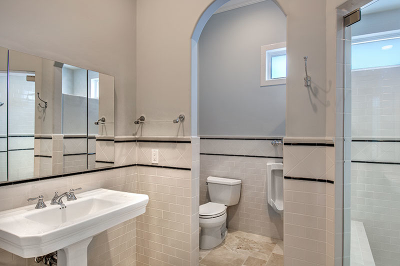 Cette image montre une salle de bain principale traditionnelle avec un lavabo encastré, un placard à porte shaker, des portes de placard blanches, un plan de toilette en marbre, une baignoire indépendante, un urinoir, un carrelage beige, des carreaux de céramique, un mur bleu et un sol en travertin.