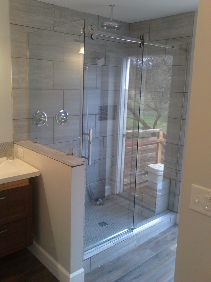 Idées déco pour une salle de bain contemporaine de taille moyenne avec une douche d'angle, un carrelage gris, des carreaux de porcelaine, parquet clair, un sol gris, une cabine de douche à porte coulissante et un plan de toilette blanc.