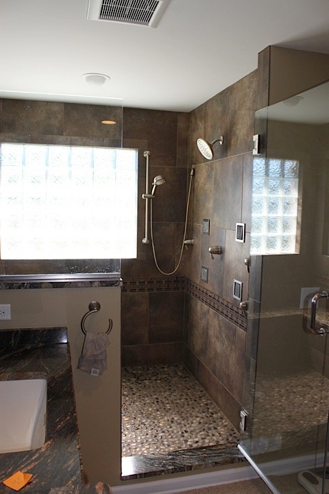 Стильный дизайн: главная ванная комната в современном стиле с двойным душем, коричневой плиткой, галечной плиткой, бежевыми стенами и полом из керамогранита - последний тренд