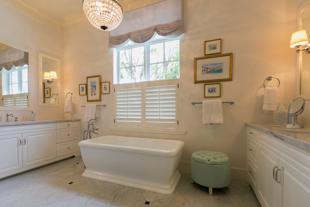 Ejemplo de cuarto de baño principal tradicional renovado grande con armarios con paneles con relieve, puertas de armario blancas, encimera de mármol, bañera exenta y suelo de mármol
