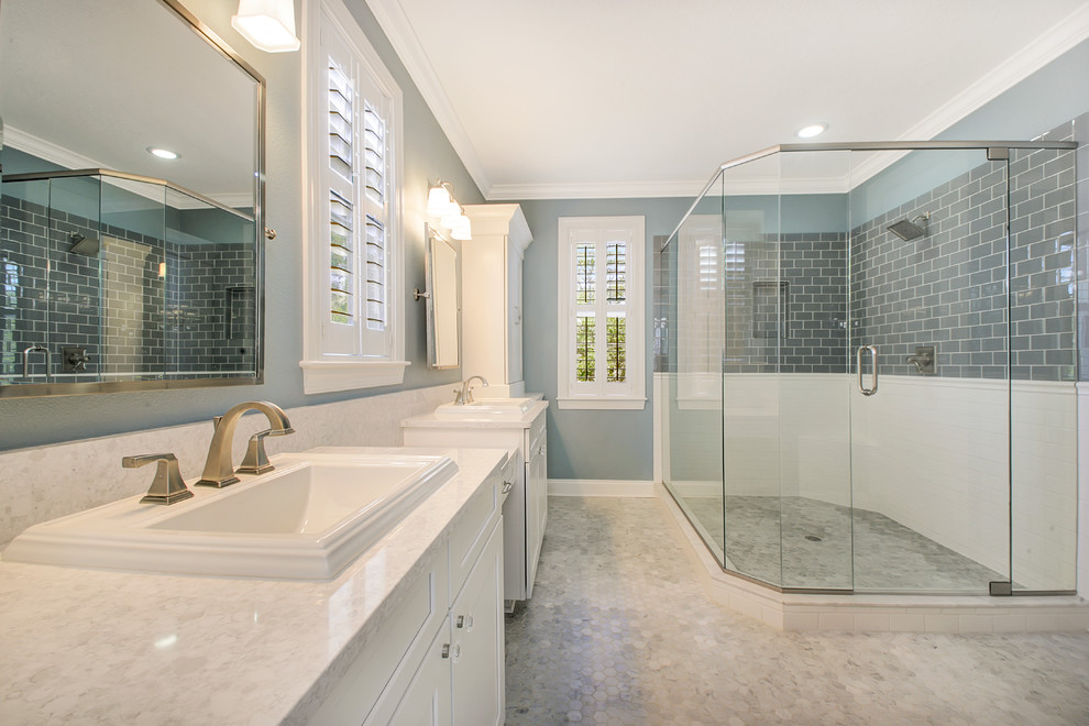 Inspiration for a large beach style ensuite bathroom in Tampa with shaker cabinets, white cabinets, a corner shower, grey tiles, glass tiles, blue walls, marble flooring, a built-in sink and engineered stone worktops.