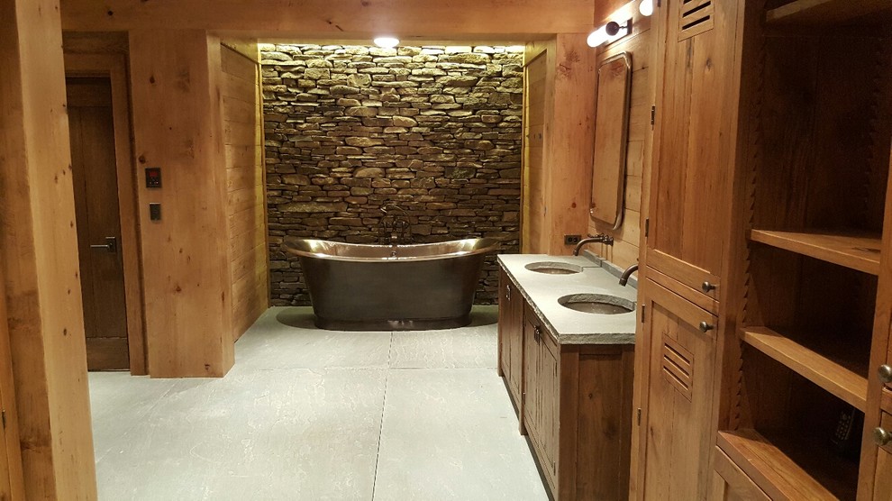 Exempel på ett stort minimalistiskt en-suite badrum, med skåp i mellenmörkt trä, ett fristående badkar, grå kakel, stenkakel, bruna väggar, cementgolv, ett undermonterad handfat, bänkskiva i kalksten och skåp i shakerstil