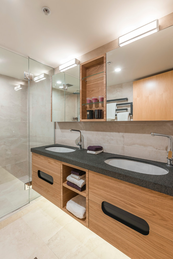 Medium sized scandi bathroom in Auckland with flat-panel cabinets, light wood cabinets, a wall mounted toilet, beige tiles, porcelain tiles, beige walls, porcelain flooring, a submerged sink, granite worktops, beige floors and a hinged door.