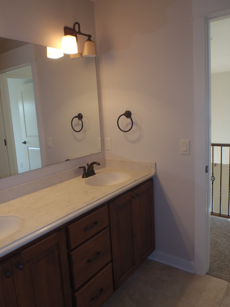 Example of a classic beige tile and ceramic tile ceramic tile tub/shower combo design in Milwaukee with a drop-in sink, raised-panel cabinets, medium tone wood cabinets, granite countertops, a two-piece toilet and beige walls