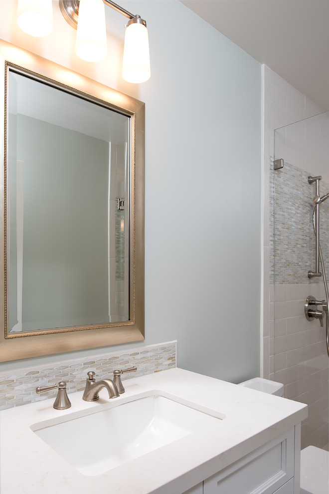 На фото: ванная комната среднего размера в стиле неоклассика (современная классика) с фасадами с утопленной филенкой, белыми фасадами, душем в нише, унитазом-моноблоком, белой плиткой, керамогранитной плиткой, синими стенами, полом из мозаичной плитки, душевой кабиной, врезной раковиной, столешницей из искусственного кварца, белым полом и душем с распашными дверями с