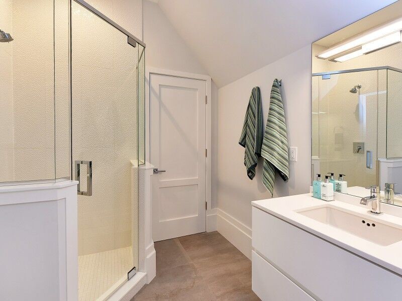 Kleines Klassisches Duschbad mit flächenbündigen Schrankfronten, weißen Schränken, Eckdusche, grauer Wandfarbe, dunklem Holzboden, Unterbauwaschbecken und Mineralwerkstoff-Waschtisch in New York