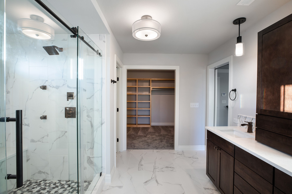 Bild på ett funkis vit vitt badrum, med luckor med infälld panel, bruna skåp, en dubbeldusch, vit kakel, marmorkakel, grå väggar, klinkergolv i keramik, bänkskiva i akrylsten, flerfärgat golv och dusch med skjutdörr