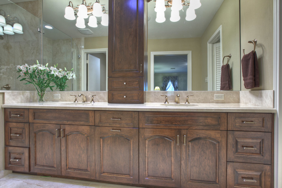 Immagine di una stanza da bagno chic con lavabo sottopiano, ante con bugna sagomata, ante in legno bruno e top in marmo