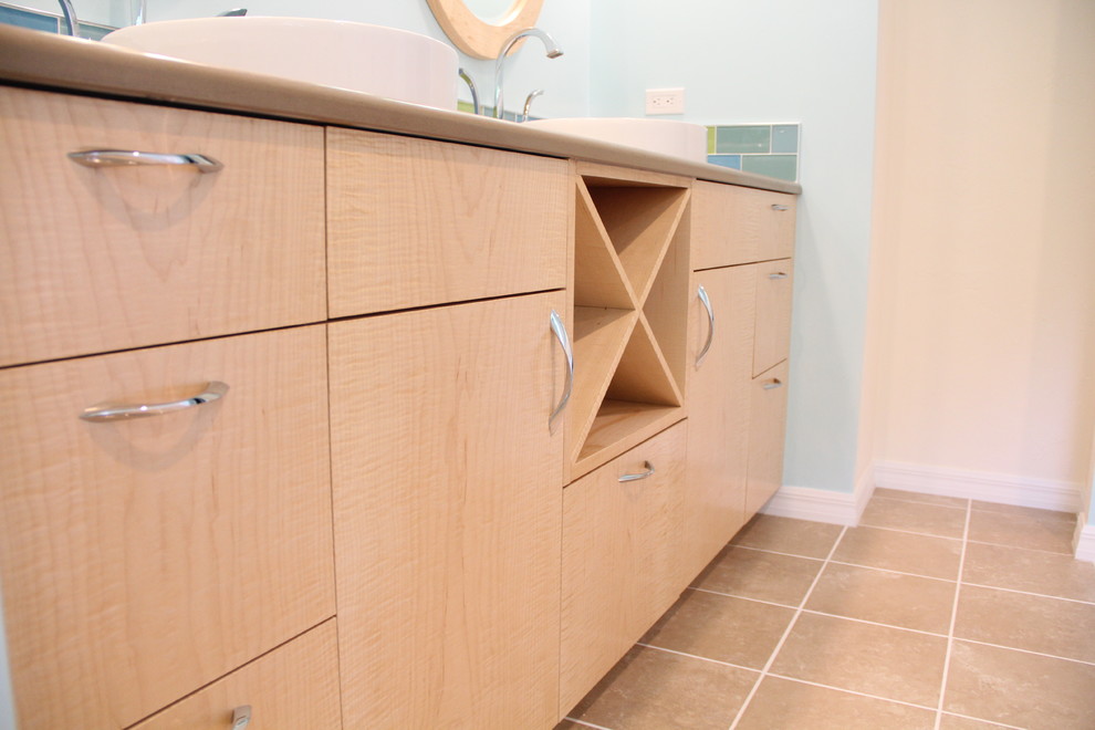 This is an example of a medium sized nautical ensuite bathroom in Miami with flat-panel cabinets, light wood cabinets, a two-piece toilet, multi-coloured tiles, glass tiles, blue walls, ceramic flooring, a vessel sink, engineered stone worktops and beige floors.