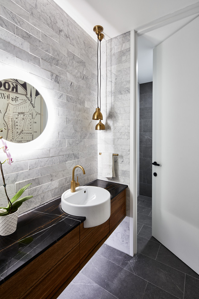 Idee per una stanza da bagno padronale contemporanea con ante lisce, ante in legno bruno, piastrelle grigie, piastrelle di marmo, pareti grigie, lavabo da incasso, pavimento nero e top nero