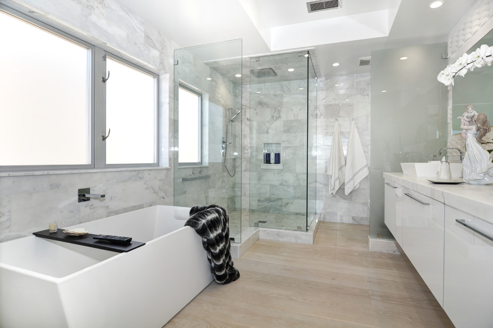 Inspiration för stora moderna en-suite badrum, med släta luckor, vita skåp, ett fristående badkar, en hörndusch, vita väggar, ljust trägolv, ett fristående handfat och marmorbänkskiva