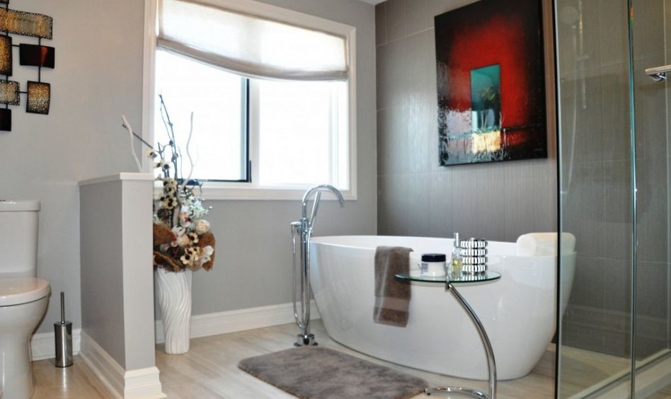 Large classic ensuite bathroom in Ottawa with a freestanding bath, a built-in shower, a two-piece toilet, grey walls and light hardwood flooring.