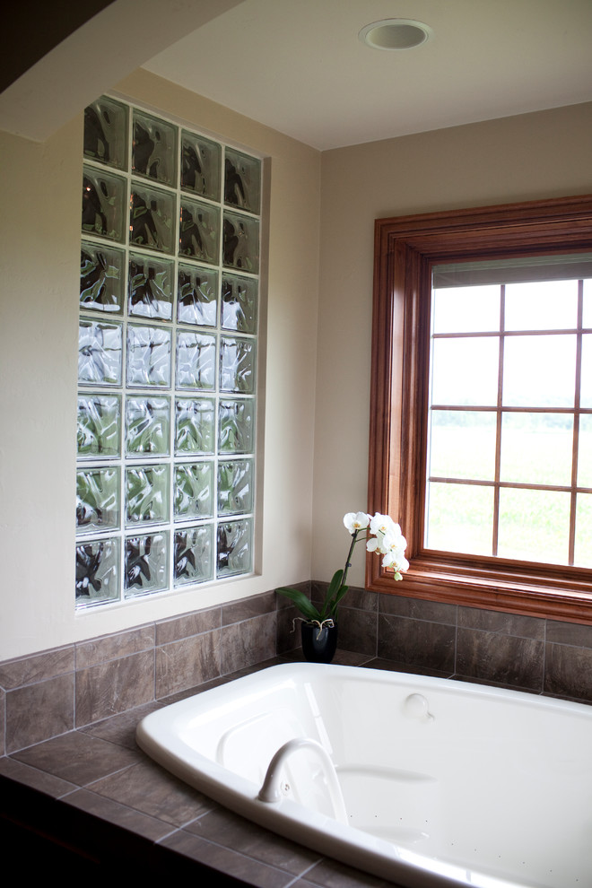 Cette photo montre une douche en alcôve principale chic en bois brun avec une baignoire posée, un placard avec porte à panneau surélevé, un carrelage gris, un mur beige et un lavabo encastré.