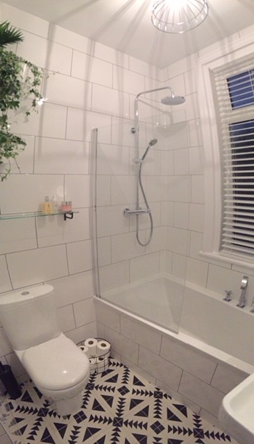Cette image montre une salle de bain minimaliste de taille moyenne pour enfant avec une baignoire posée, WC à poser, un carrelage noir et blanc, un mur blanc et un sol en carrelage de céramique.