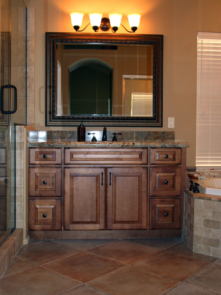 Bathroom - large traditional master beige tile and porcelain tile porcelain tile and brown floor bathroom idea in Phoenix with raised-panel cabinets, medium tone wood cabinets, granite countertops, beige walls, an undermount sink and a hinged shower door