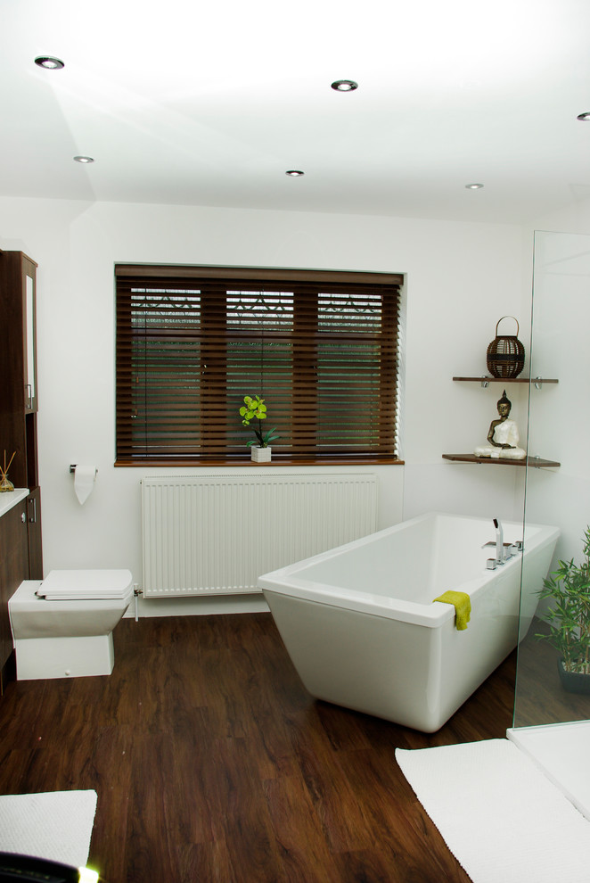 Ejemplo de cuarto de baño actual con armarios con paneles lisos, puertas de armario de madera en tonos medios y bañera exenta