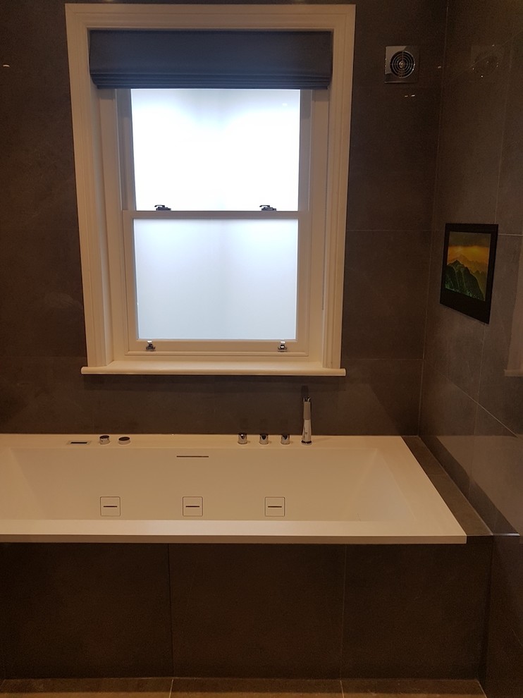 Design ideas for a large contemporary ensuite bathroom in London with open cabinets, brown cabinets, a built-in bath, an alcove shower, a wall mounted toilet, brown tiles, porcelain tiles, brown walls, porcelain flooring, a submerged sink, quartz worktops, brown floors and a hinged door.