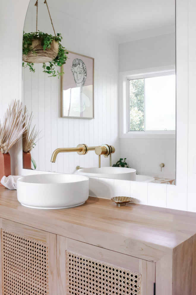 Cette image montre une salle de bain marine avec des portes de placard blanches et un plan de toilette en bois.