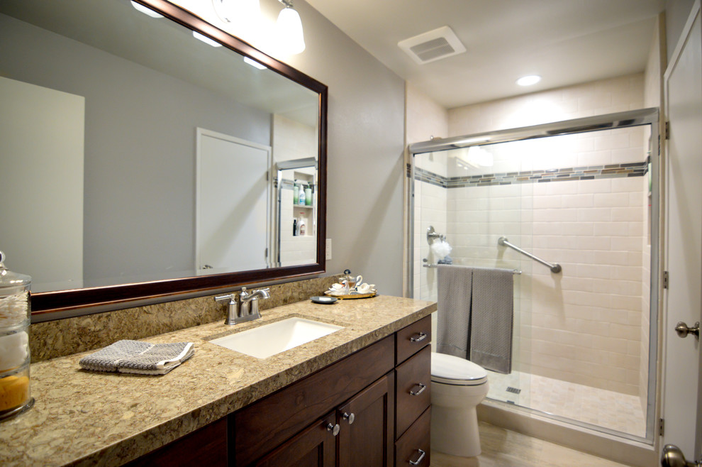 Bathroom - mid-sized transitional beige tile porcelain tile and multicolored floor bathroom idea in Orange County with recessed-panel cabinets, dark wood cabinets, a two-piece toilet, gray walls, an undermount sink, quartz countertops and brown countertops