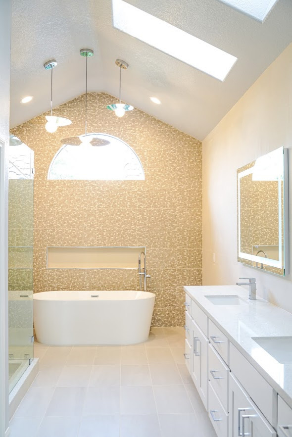 Photo of a medium sized modern ensuite bathroom in Orange County with flat-panel cabinets, white cabinets, a freestanding bath, a corner shower, beige tiles, porcelain tiles, beige walls, porcelain flooring, a built-in sink, engineered stone worktops, beige floors, a hinged door and white worktops.