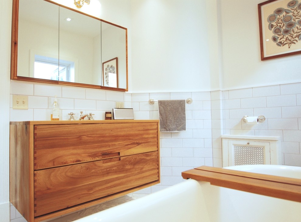 Пример оригинального дизайна: главная ванная комната среднего размера в современном стиле с ванной на ножках, открытым душем, белой плиткой, керамогранитной плиткой, белыми стенами, мраморным полом, врезной раковиной, белым полом, открытым душем, плоскими фасадами, светлыми деревянными фасадами, столешницей из дерева и коричневой столешницей