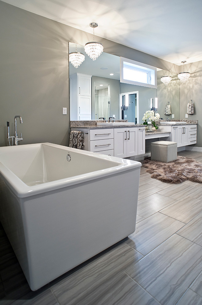 Klassisk inredning av ett stort en-suite badrum, med vita skåp, ett fristående badkar, beige kakel, grå väggar, ett fristående handfat, granitbänkskiva, skåp i shakerstil, en dusch i en alkov och dusch med gångjärnsdörr