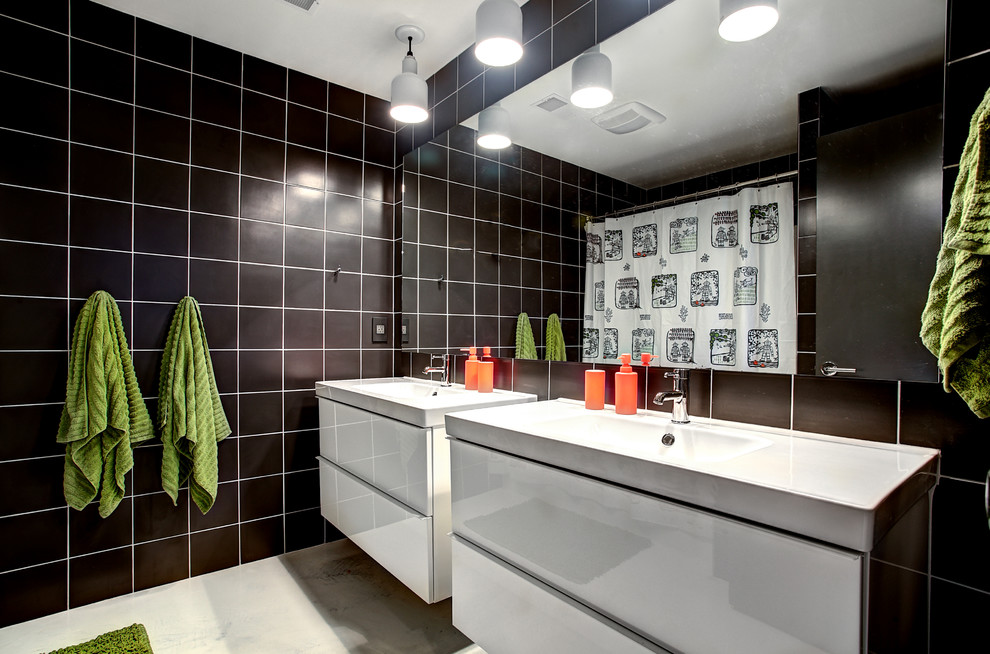 На фото: детская ванная комната среднего размера в современном стиле с монолитной раковиной, плоскими фасадами, белыми фасадами, черной плиткой, каменной плиткой и бетонным полом с