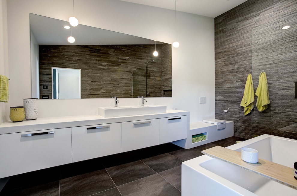 Стильный дизайн: большая главная ванная комната в современном стиле с плоскими фасадами, белыми фасадами, отдельно стоящей ванной, инсталляцией, серой плиткой, каменной плиткой, белыми стенами и раковиной с несколькими смесителями - последний тренд