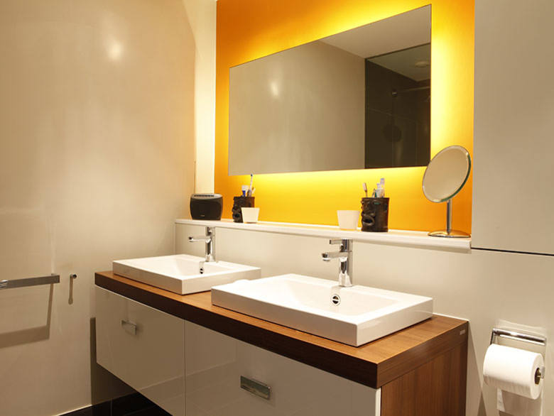 Foto di una stanza da bagno contemporanea con ante lisce, ante in legno chiaro, doccia aperta, pareti arancioni, pavimento con piastrelle in ceramica, lavabo integrato, top in laminato, pavimento grigio e doccia aperta