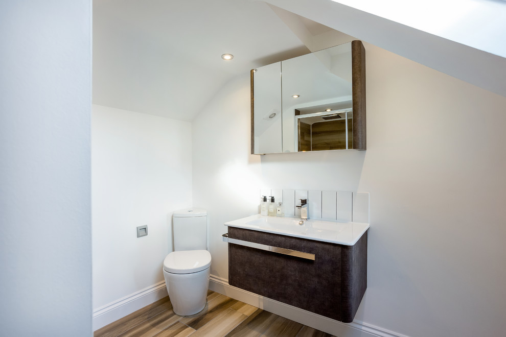 Пример оригинального дизайна: ванная комната в современном стиле с плоскими фасадами, черными фасадами, раздельным унитазом, белыми стенами, паркетным полом среднего тона, душевой кабиной, монолитной раковиной, коричневым полом и белой столешницей