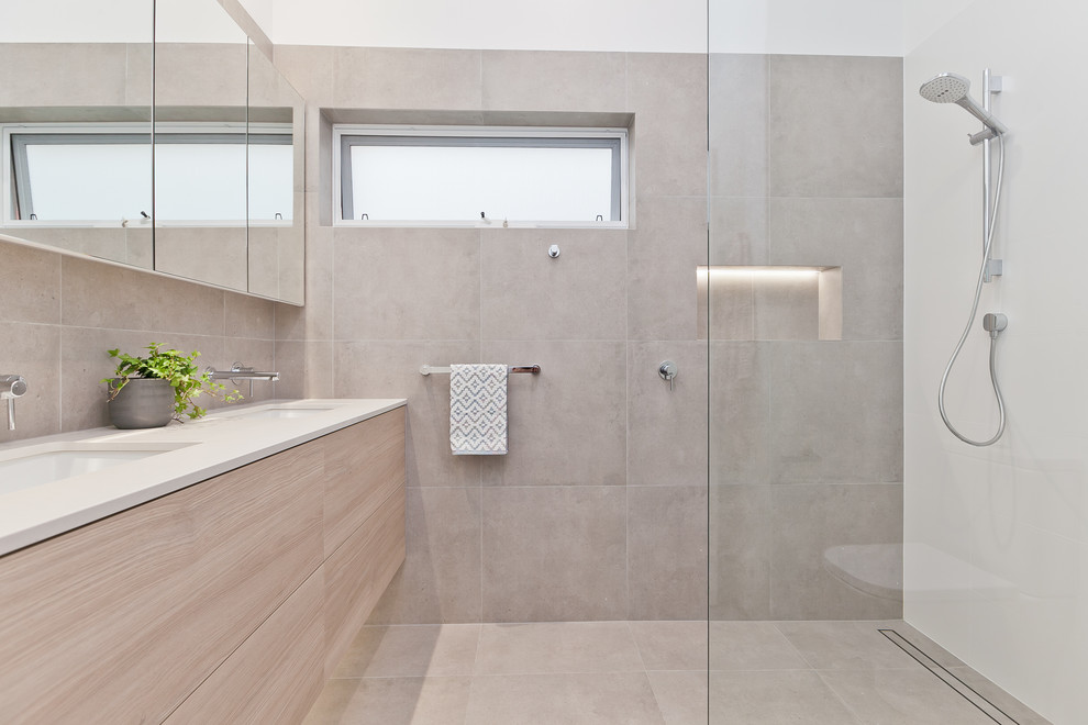 Example of a mid-sized trendy master gray tile and porcelain tile porcelain tile and gray floor corner shower design in Perth with light wood cabinets, a one-piece toilet, white walls, an undermount sink, quartz countertops, a hinged shower door and white countertops