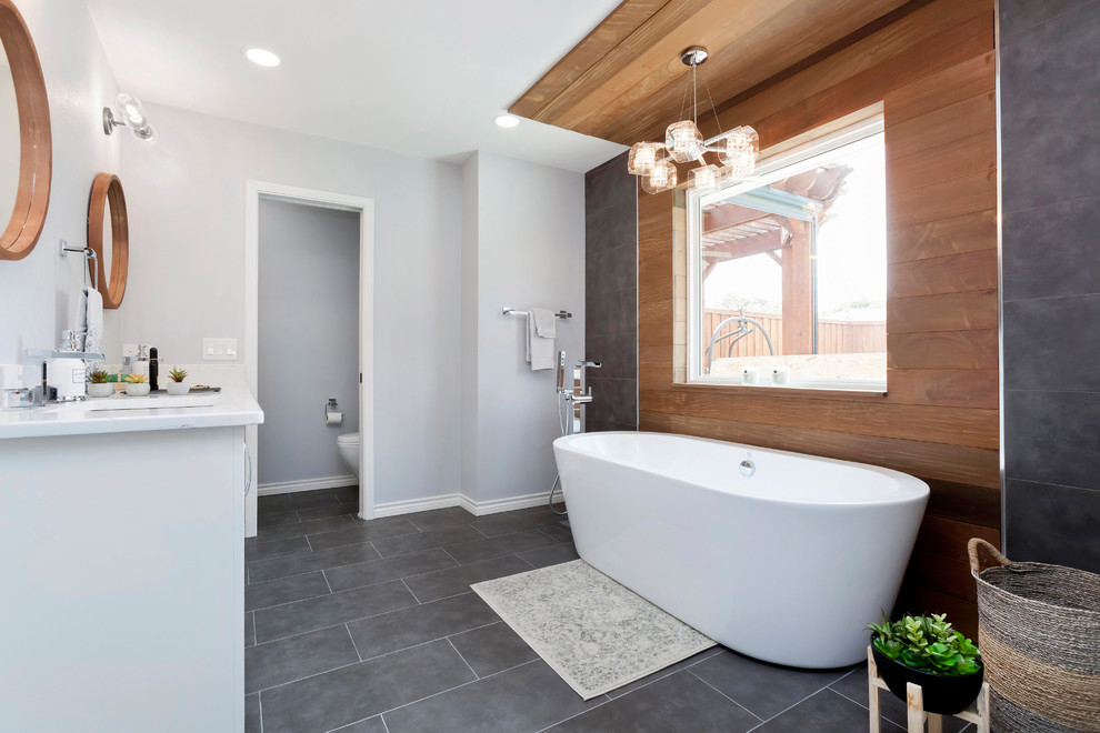 Inspiration for a medium sized contemporary ensuite bathroom in Dallas with shaker cabinets, white cabinets, a freestanding bath, a double shower, a one-piece toilet, grey tiles, porcelain tiles, grey walls, porcelain flooring, a built-in sink, grey floors, a hinged door, marble worktops and white worktops.