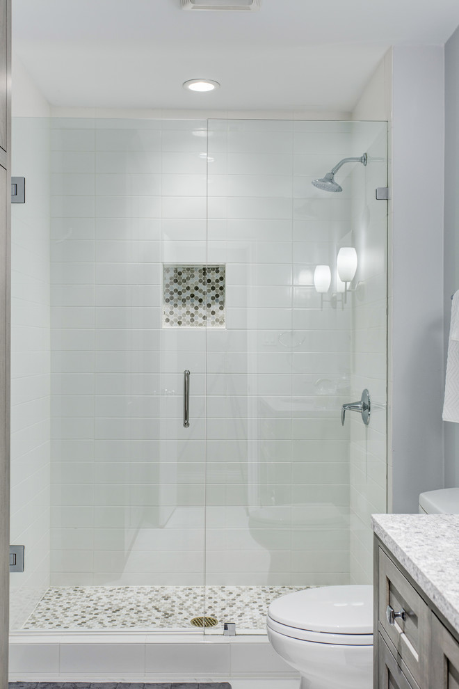 Modern inredning av ett badrum med dusch, med luckor med infälld panel, grå skåp, en dusch i en alkov, en toalettstol med separat cisternkåpa, vit kakel, keramikplattor, grå väggar, klinkergolv i porslin, ett undermonterad handfat och bänkskiva i kvartsit