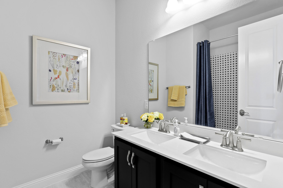 Exempel på ett mellanstort modernt vit vitt badrum för barn, med luckor med infälld panel, svarta skåp, en dusch/badkar-kombination, svart och vit kakel, keramikplattor, vita väggar, klinkergolv i keramik, ett undermonterad handfat, bänkskiva i akrylsten, grått golv och dusch med duschdraperi