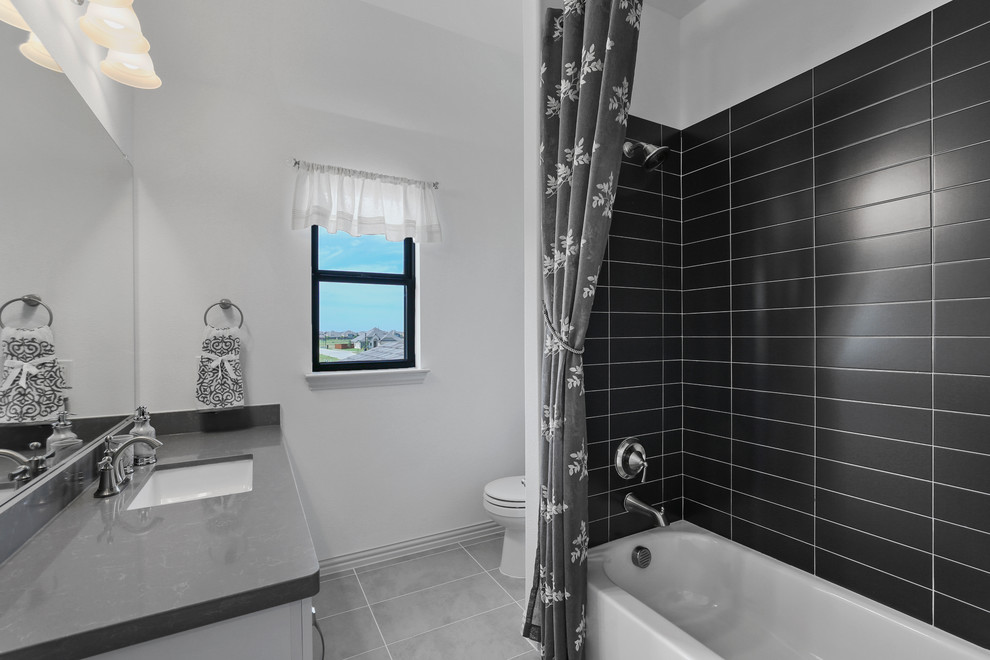 Exempel på ett mellanstort modernt grå grått badrum för barn, med luckor med infälld panel, en dusch/badkar-kombination, svart kakel, keramikplattor, vita väggar, klinkergolv i keramik, ett undermonterad handfat, bänkskiva i akrylsten, grått golv, dusch med duschdraperi och vita skåp
