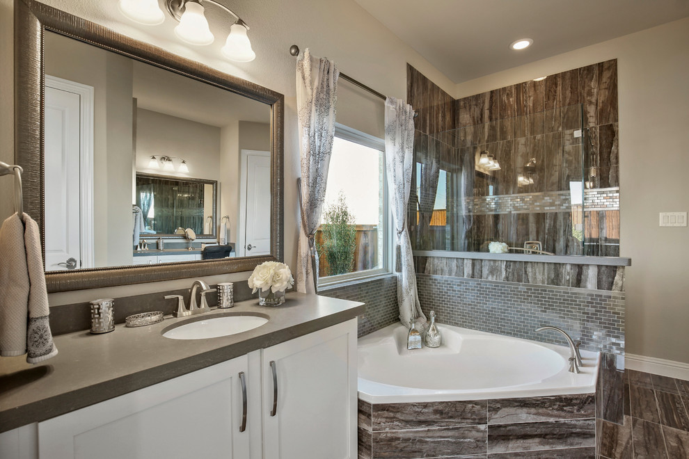 Inspiration for a large rustic ensuite bathroom in Dallas with recessed-panel cabinets, white cabinets, a corner bath, a corner shower, grey tiles, ceramic tiles, beige walls, ceramic flooring, a submerged sink, solid surface worktops, grey floors and a hinged door.