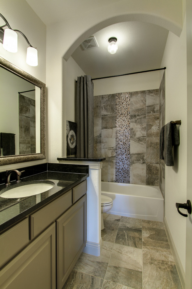 Foto på ett mellanstort badrum med dusch, med luckor med upphöjd panel, grå skåp, ett badkar i en alkov, en dusch/badkar-kombination, grå kakel, glaskakel, beige väggar, klinkergolv i porslin, ett undermonterad handfat och granitbänkskiva