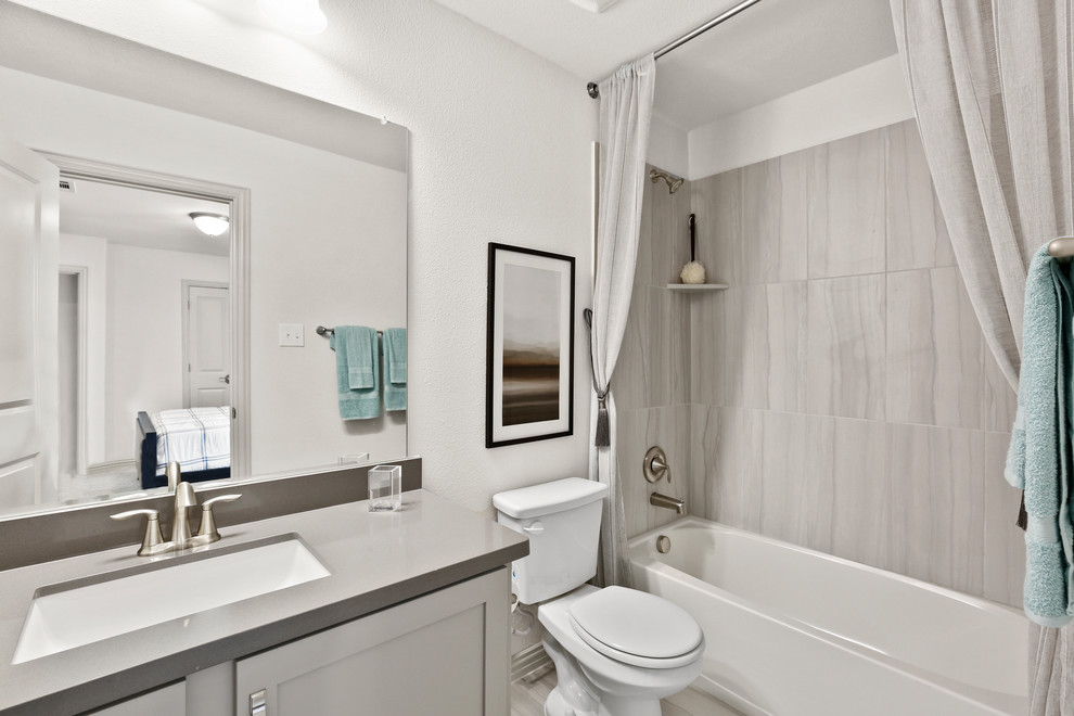Inredning av ett modernt mellanstort grå grått badrum för barn, med luckor med infälld panel, grå skåp, en dusch/badkar-kombination, keramikplattor, vita väggar, klinkergolv i keramik, bänkskiva i akrylsten, dusch med duschdraperi, grå kakel, ett undermonterad handfat och grått golv