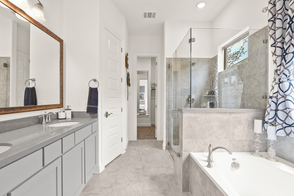 This is an example of a medium sized contemporary ensuite bathroom in Dallas with recessed-panel cabinets, grey cabinets, beige tiles, ceramic tiles, white walls, solid surface worktops, a shower curtain, double sinks, a built-in bath, a corner shower, ceramic flooring, a submerged sink, beige floors and grey worktops.
