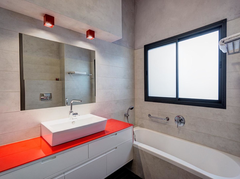 Aménagement d'une salle de bain contemporaine avec une vasque, un placard à porte plane, des portes de placard blanches, une baignoire en alcôve et un carrelage gris.