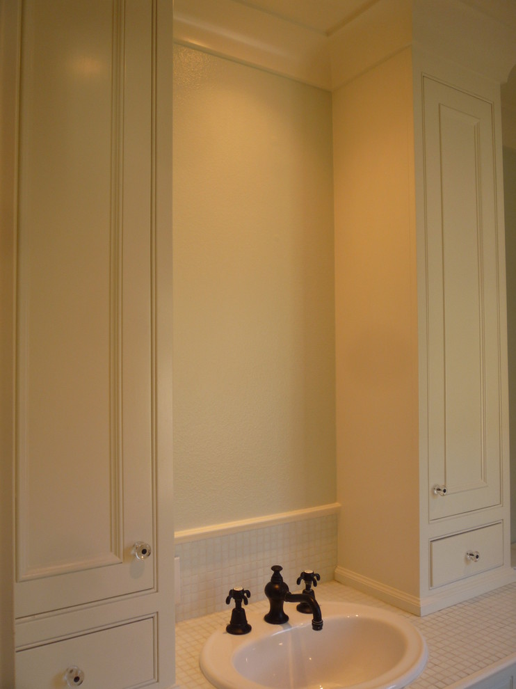 Bild på ett mellanstort lantligt badrum för barn, med ett nedsänkt handfat, luckor med infälld panel, vita skåp, kaklad bänkskiva, ett platsbyggt badkar, en dusch/badkar-kombination, en toalettstol med separat cisternkåpa, vit kakel, glaskakel, vita väggar och mosaikgolv