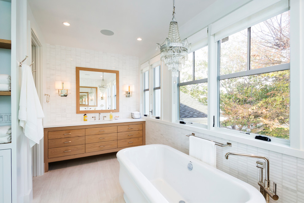 Exempel på ett klassiskt badrum, med ett undermonterad handfat, släta luckor, skåp i mellenmörkt trä, ett fristående badkar och vit kakel