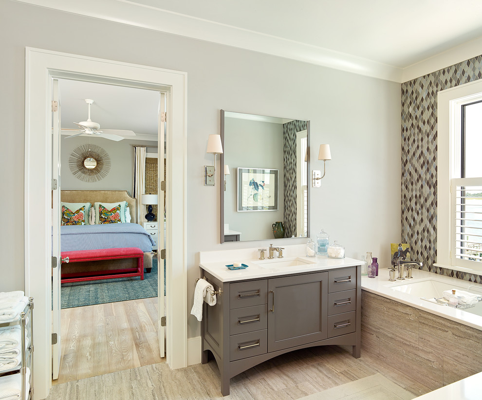 Exemple d'une salle de bain bord de mer avec un lavabo encastré, des portes de placard grises, une baignoire encastrée, un carrelage multicolore, un mur gris et un placard avec porte à panneau encastré.