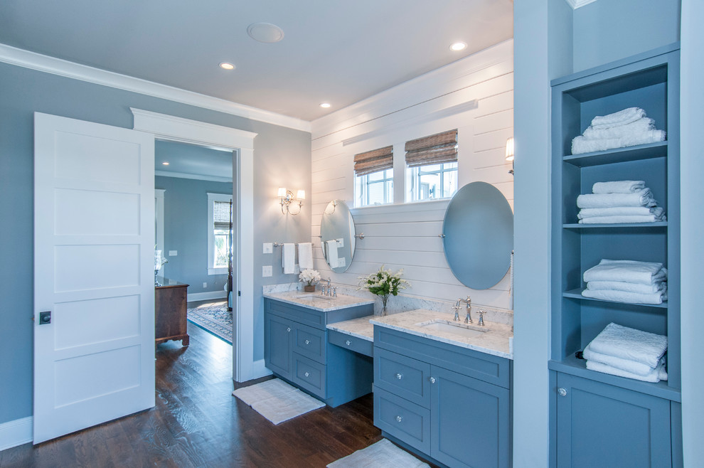 Idée de décoration pour une douche en alcôve tradition avec un lavabo encastré, des portes de placard bleues, un plan de toilette en marbre, une baignoire indépendante, un carrelage gris, un mur gris et parquet foncé.