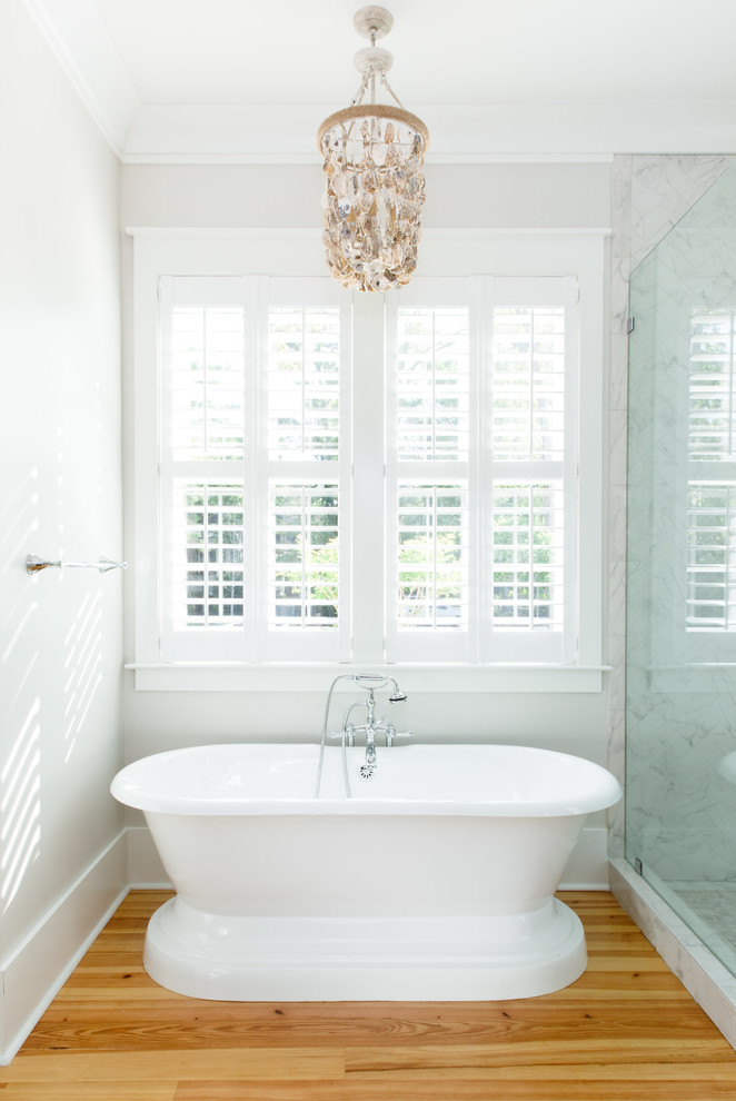 Cette photo montre une douche en alcôve principale chic de taille moyenne avec une baignoire indépendante, un carrelage gris, du carrelage en marbre, un mur blanc, parquet clair, un sol beige et une cabine de douche à porte battante.