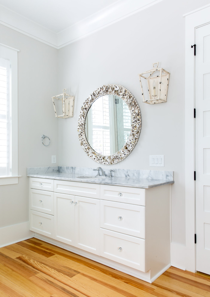 Klassisk inredning av ett mellanstort en-suite badrum, med vita skåp, ett undermonterad handfat, luckor med infälld panel, ett fristående badkar, en dusch i en alkov, grå kakel, marmorkakel, vita väggar, ljust trägolv, marmorbänkskiva, beiget golv och dusch med gångjärnsdörr