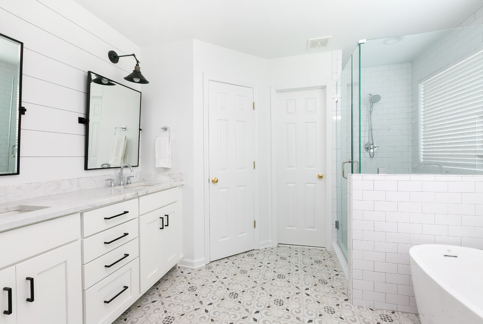 Foto på ett mellanstort lantligt en-suite badrum, med vita skåp, ett fristående badkar, vit kakel, keramikplattor, vita väggar, cementgolv, ett undermonterad handfat, grått golv och dusch med gångjärnsdörr